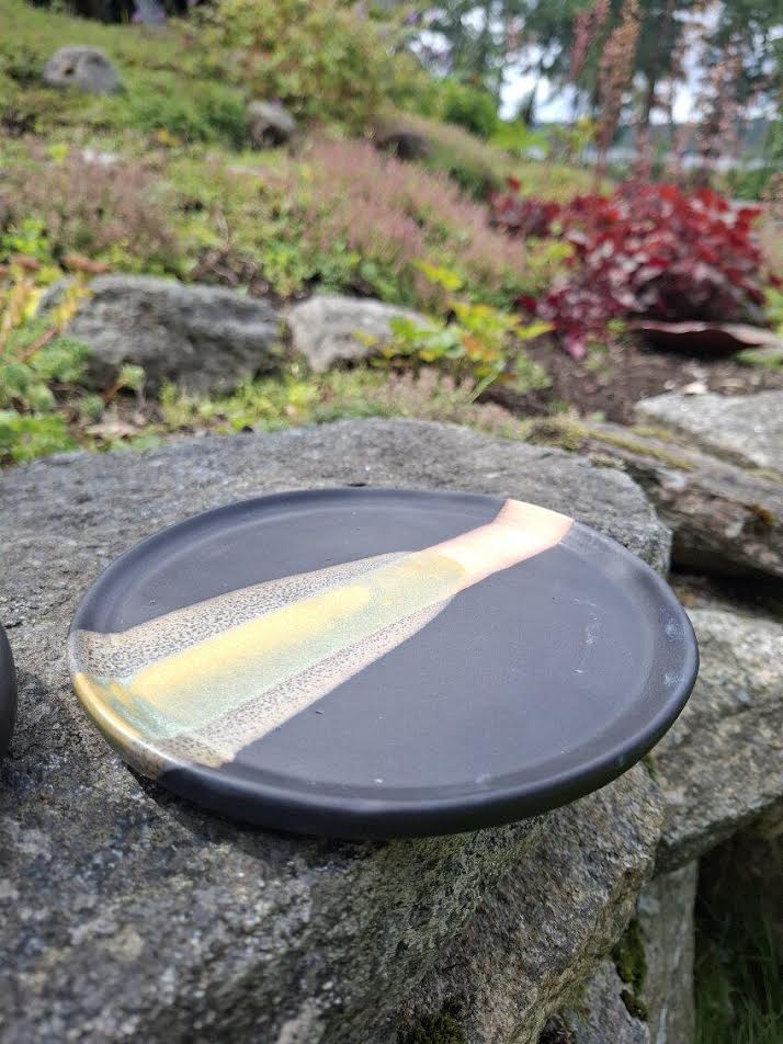 Svart fat med penseldekor i olika nyanser i strimma